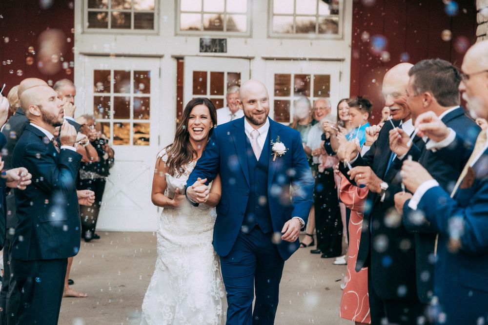 Wedding guests celebrate with bubbles as newlyweds exit the ceremony venue.