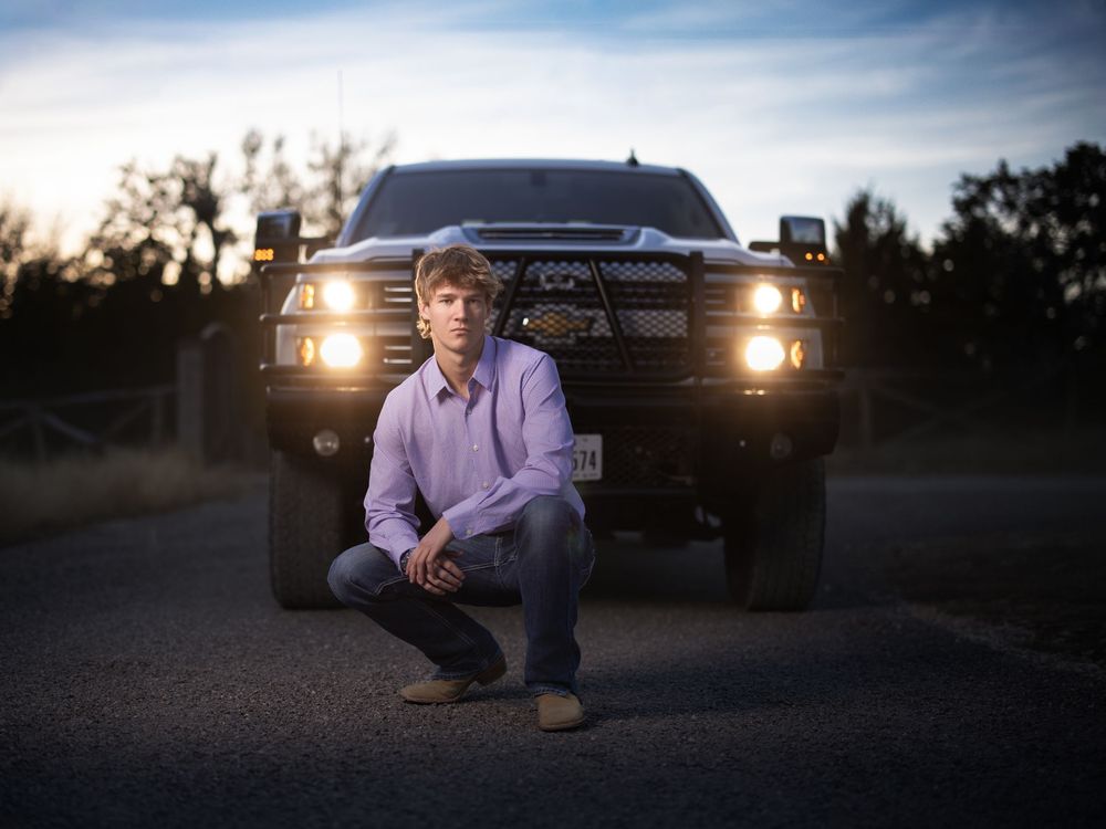 A silhouette of a vehicle with headlights on during sunset creates a dramatic backlit scene.