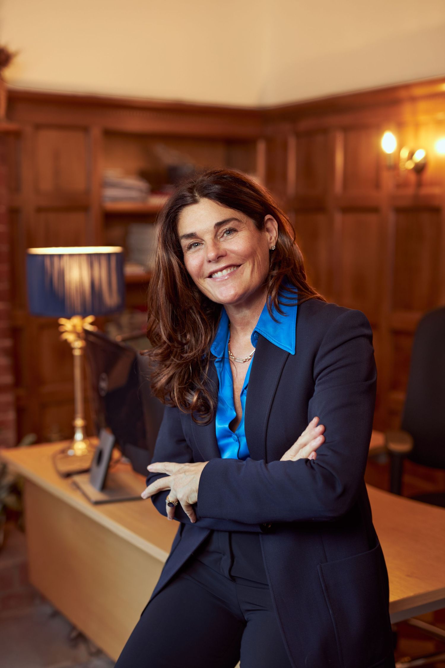 Professional portrait in wood-paneled office with warm lighting.