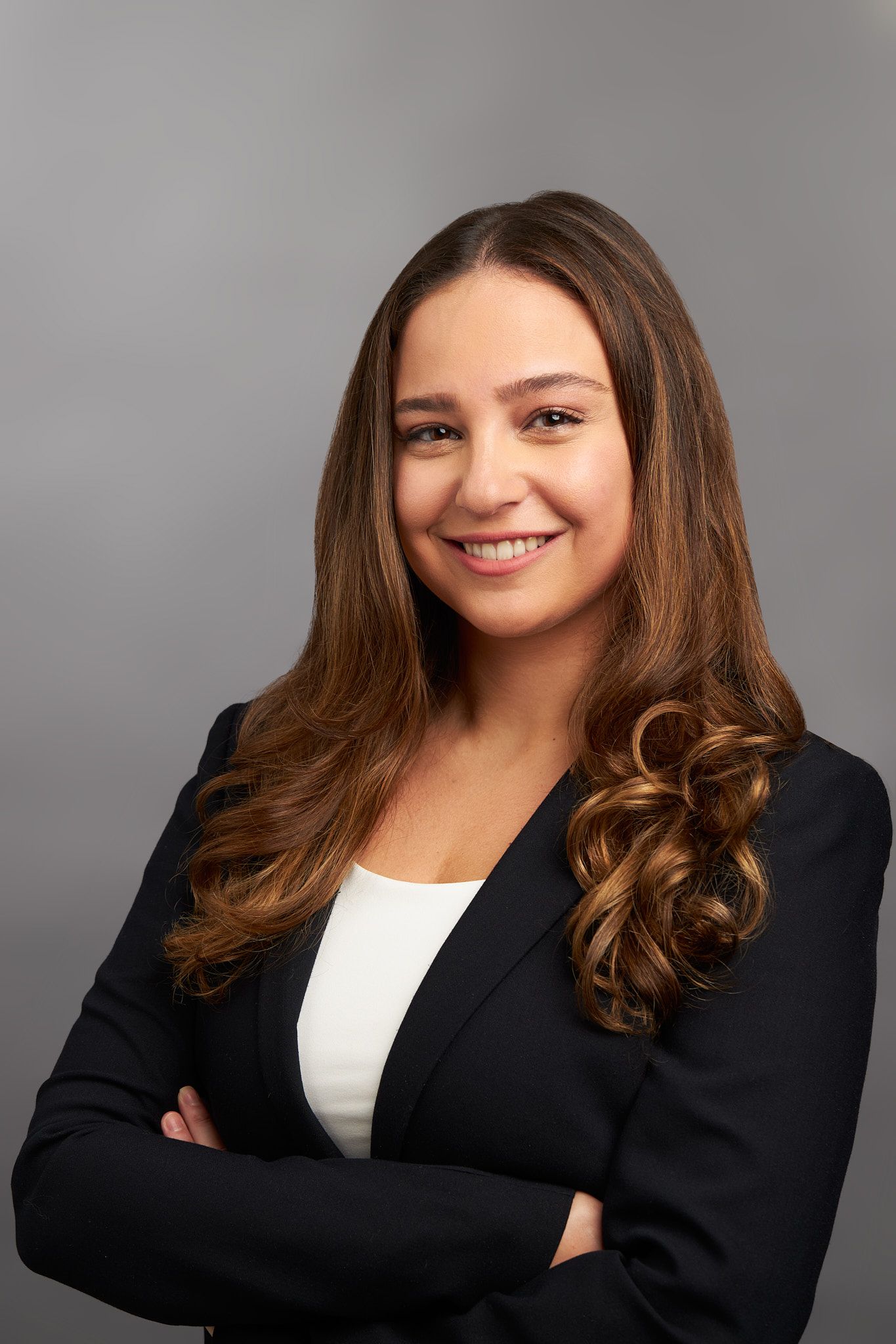 Professional headshot of a woman in business attire against grey background.