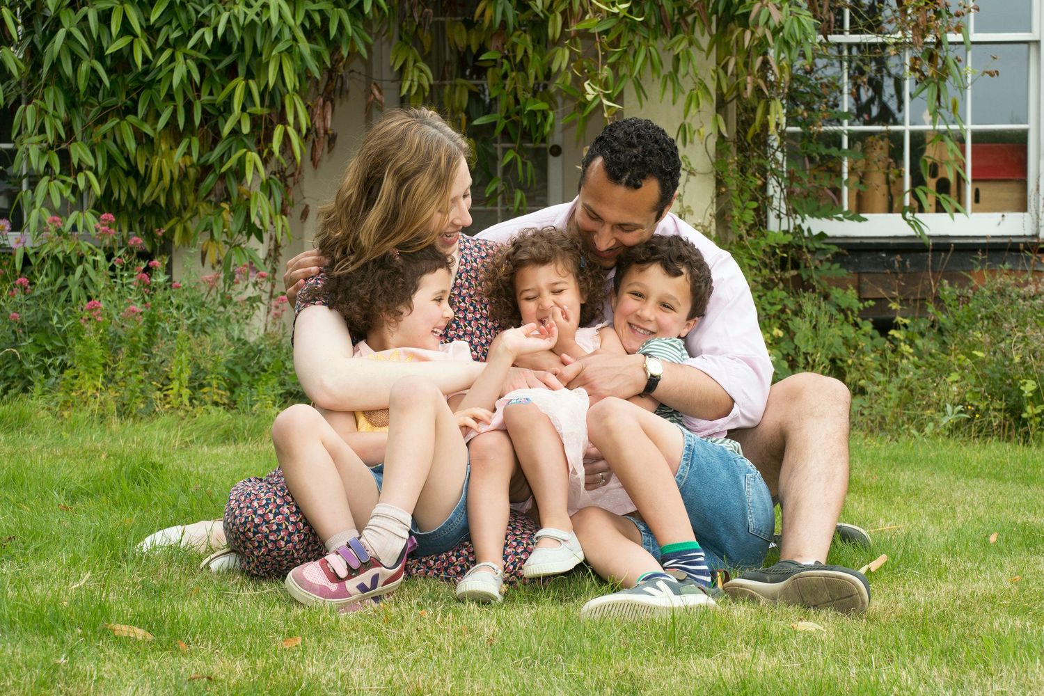 A family poses together on the grass for a photoshoot in Buckinghamshire, surrounded by nature. Photograph created by Abigail's Studio