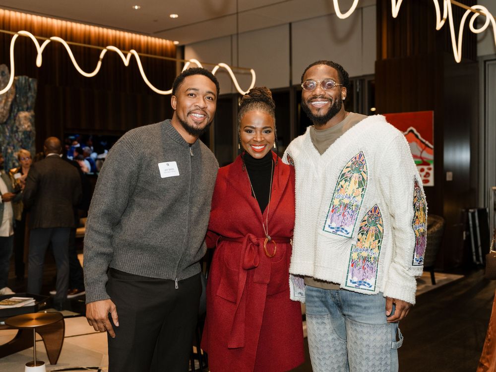 People gather at an indoor event wearing casual and business attire while smiling and socializing.