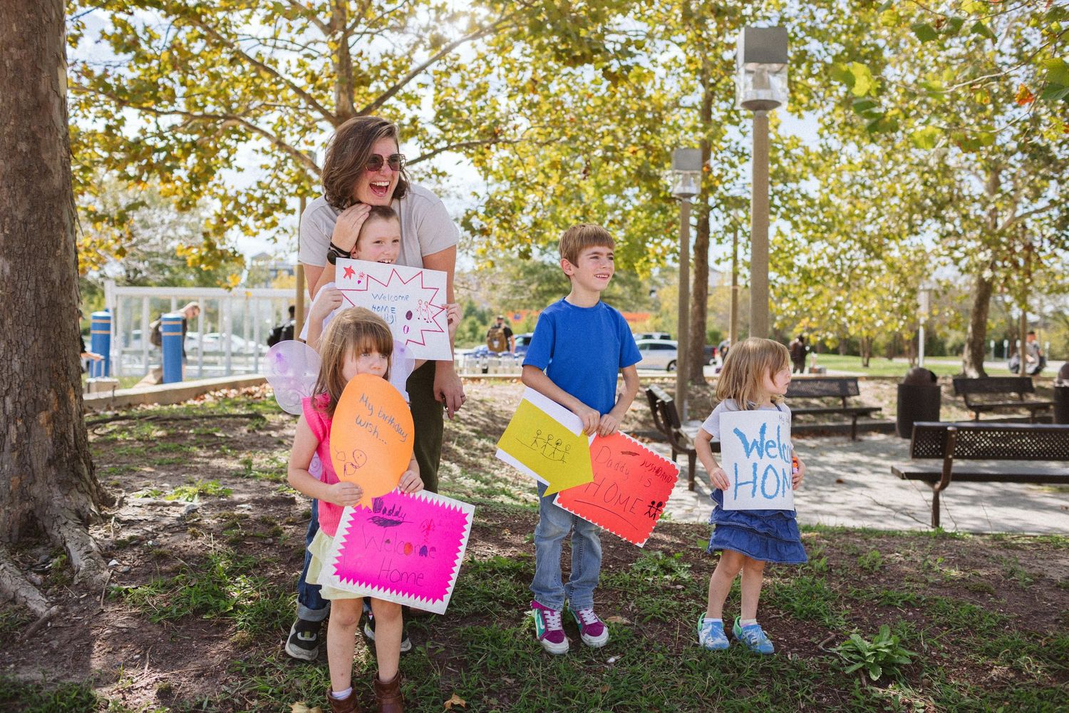 Children waiting with signs at the airport to welcome their dad home from military service in norfolk, virginia