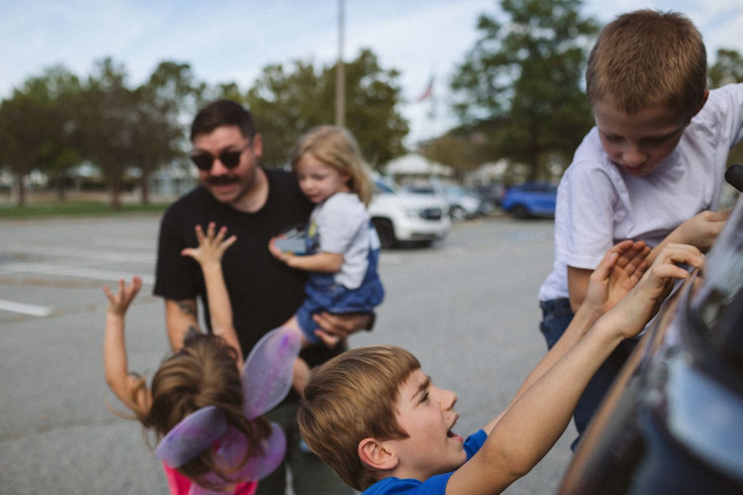 children crawling all over dad in airport parking lot for military homecoming in norfolk, virginia