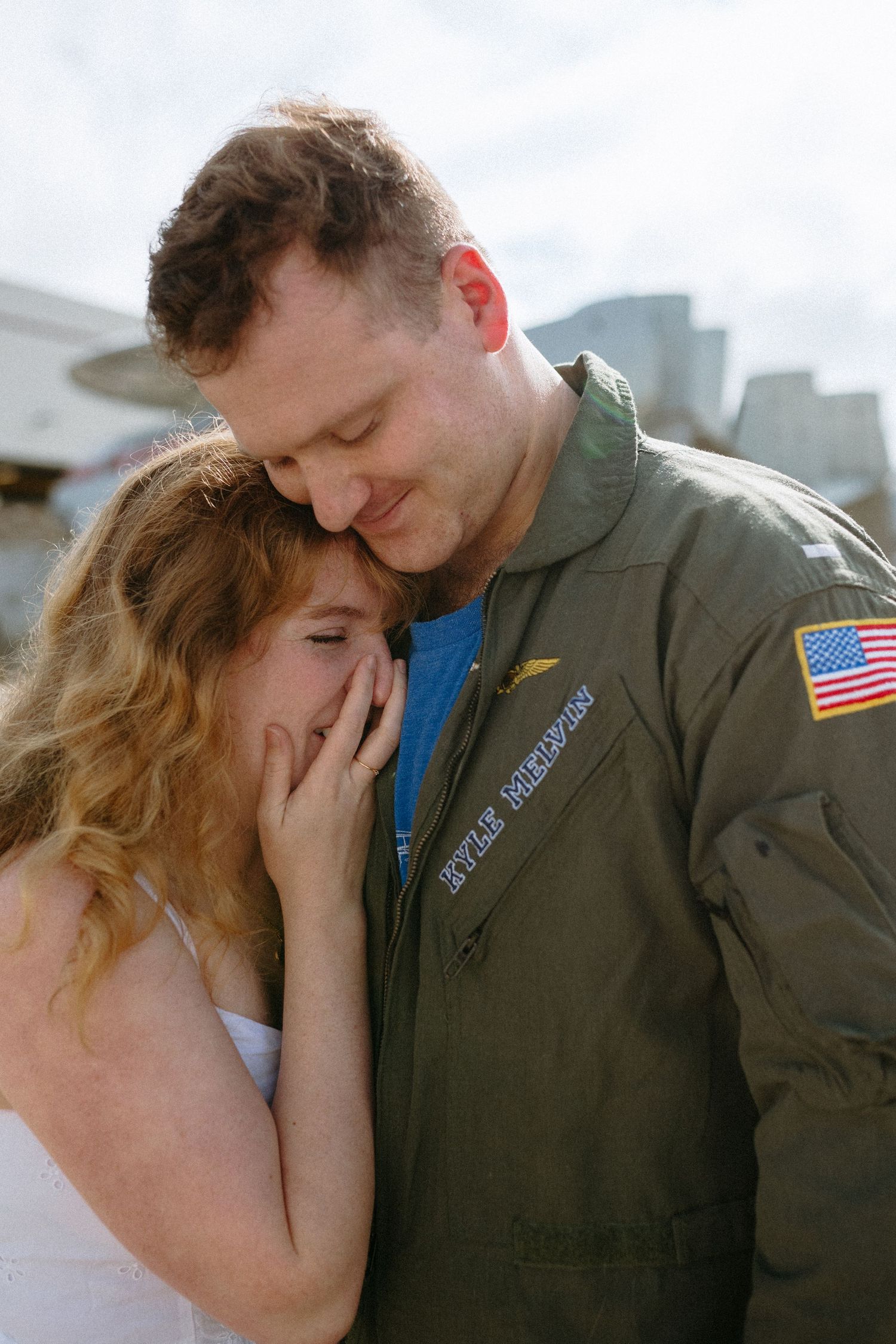 A couple embraces emotionally, with one wearing a military uniform with an American flag patch at fly in homecoming in virginia beach, va