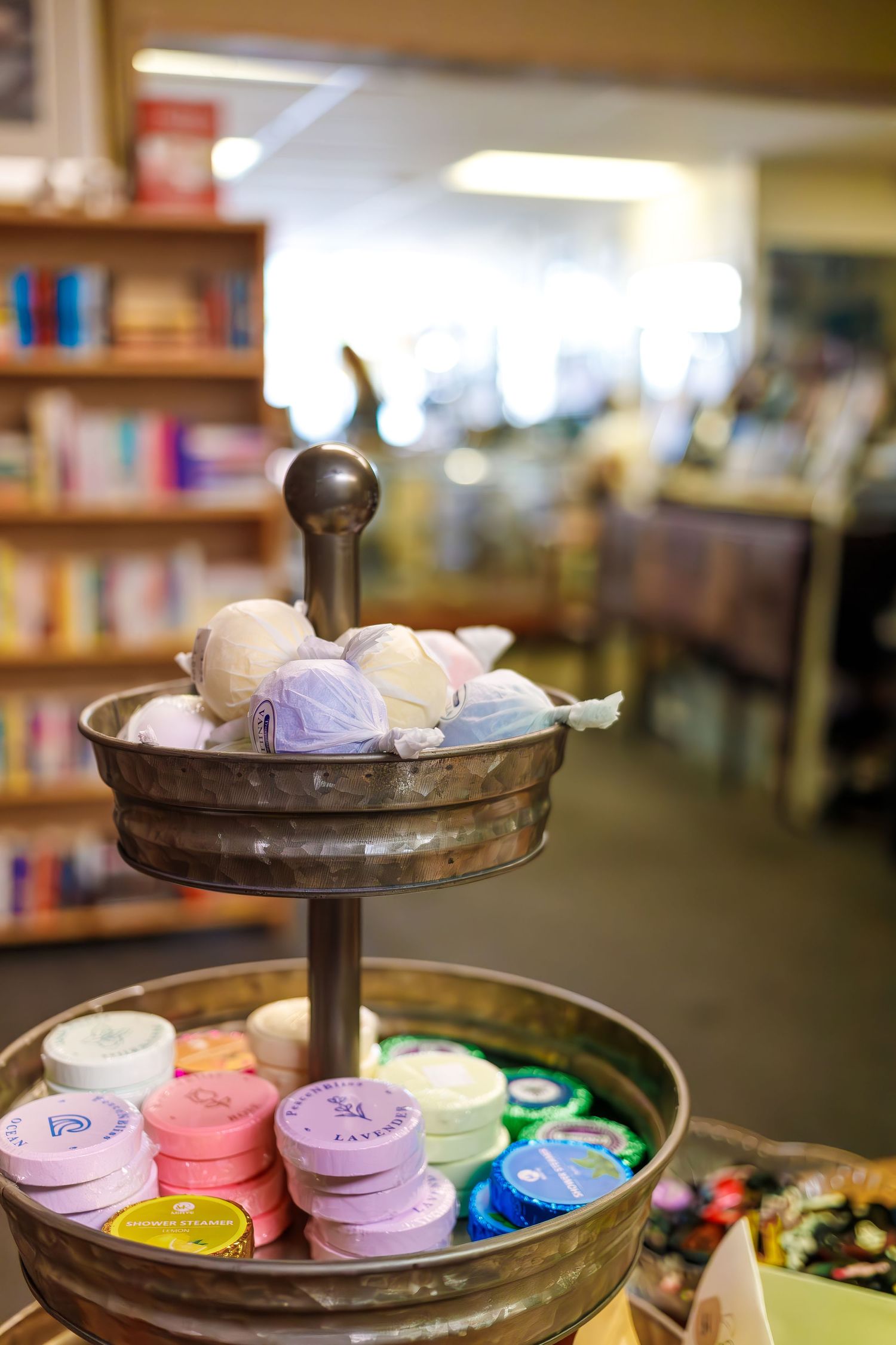 Vintage metal tiered display stand with colorful bath bombs and soaps in a bookstore setting.