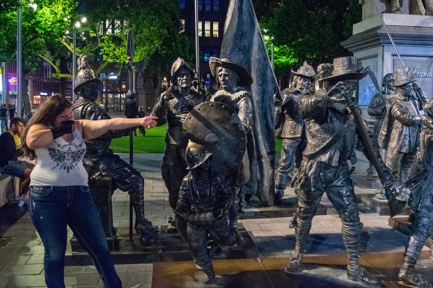 Silver-painted street performers pose dramatically in an evening city scene.