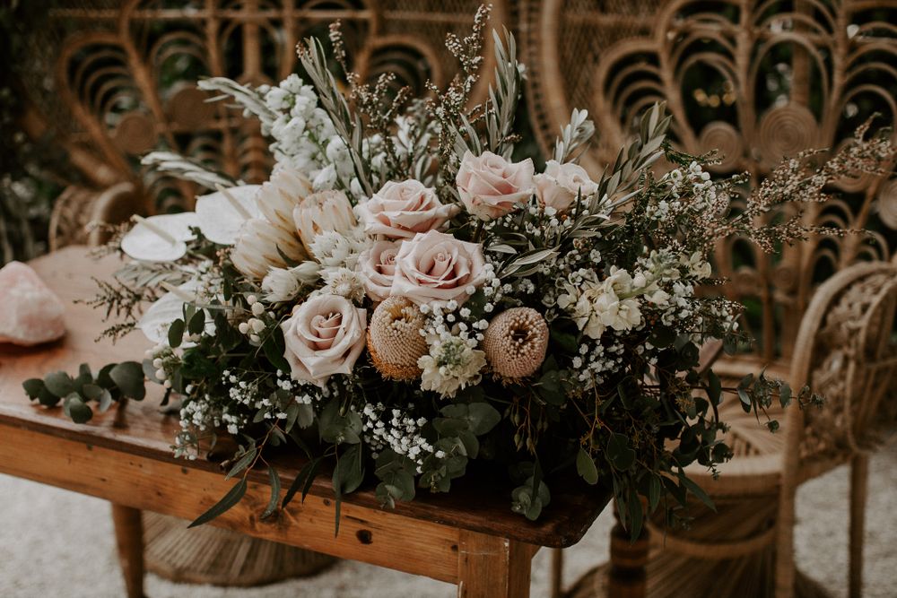 Romantic floral arrangement with pink roses and baby's breath on wooden surface.