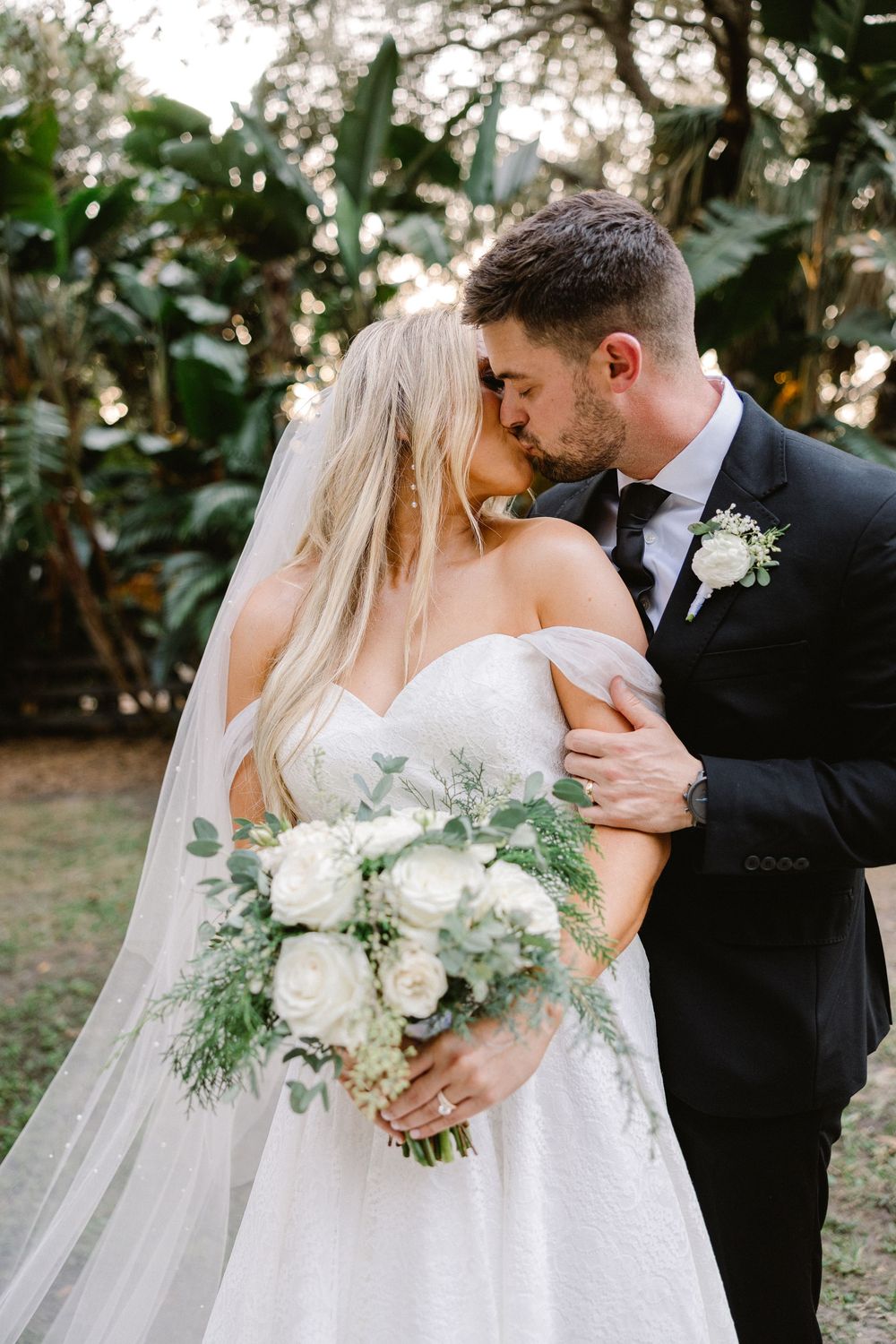 Romantic wedding portrait with white roses and greenery bouquet.