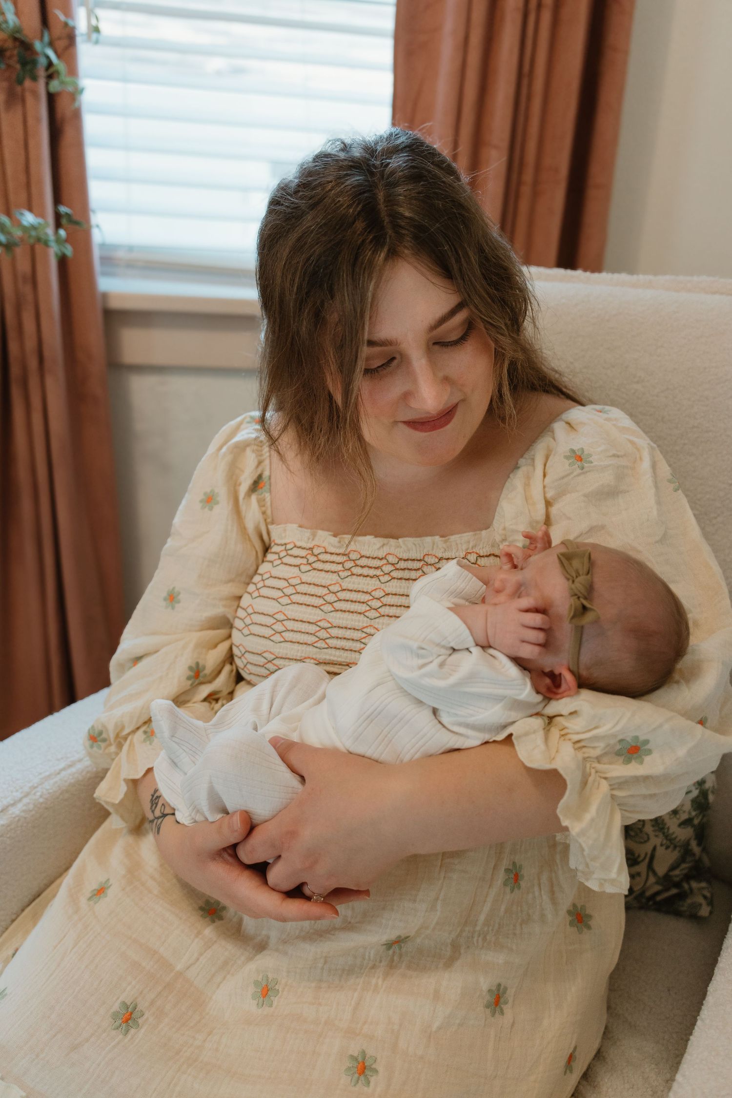 Tender moments captured in vintage-style dress while holding an infant indoors.