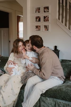 Intimate family moments shared on a gray couch with framed photos visible in background.