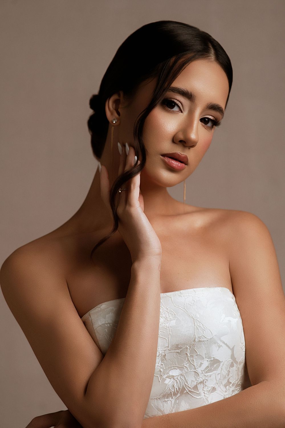Elegant bridal portrait series showing a strapless white lace gown against a neutral studio backdrop.