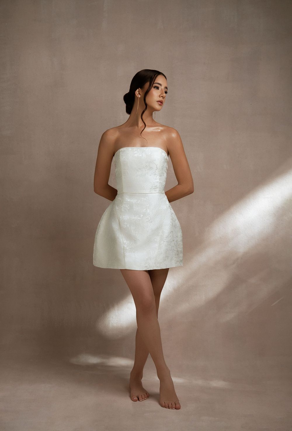 Artistic photo series showing a model in white fabric posed against a neutral backdrop with dramatic lighting effects.