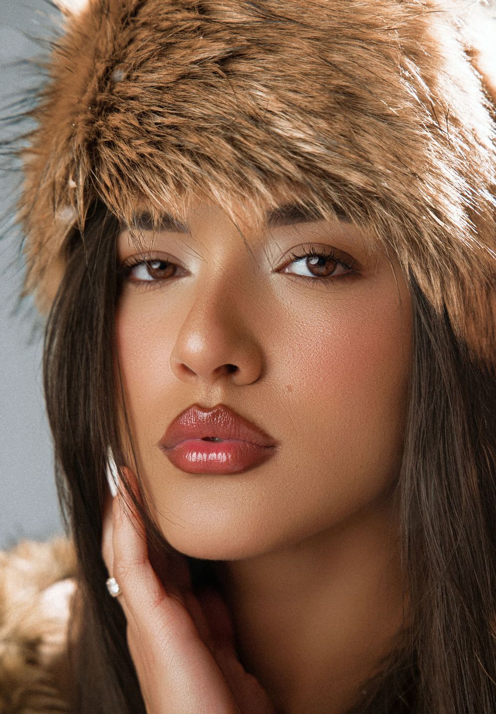 Close-up portrait of woman wearing fur hat with natural glam makeup.