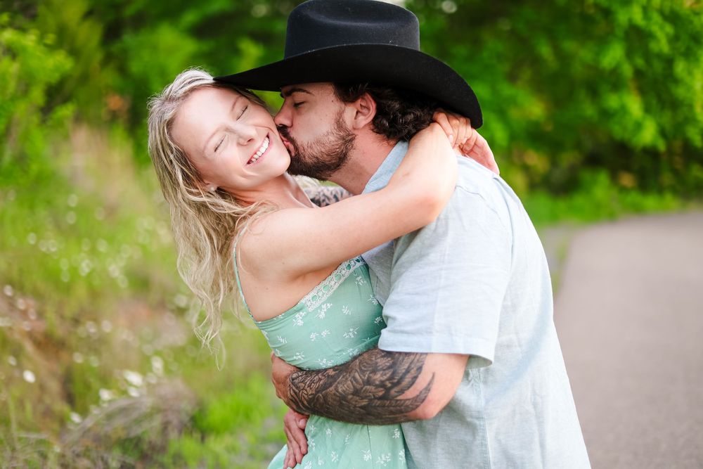 A candid image of a man kissing his fiance on the cheek during sunset.