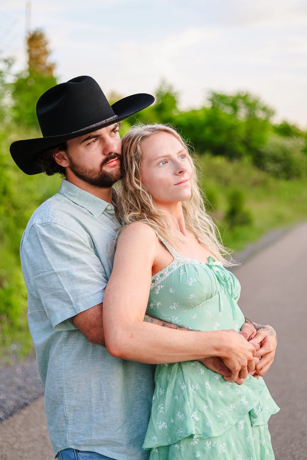A lifestyle image of a couple holding each other looking off to the side at sunset.