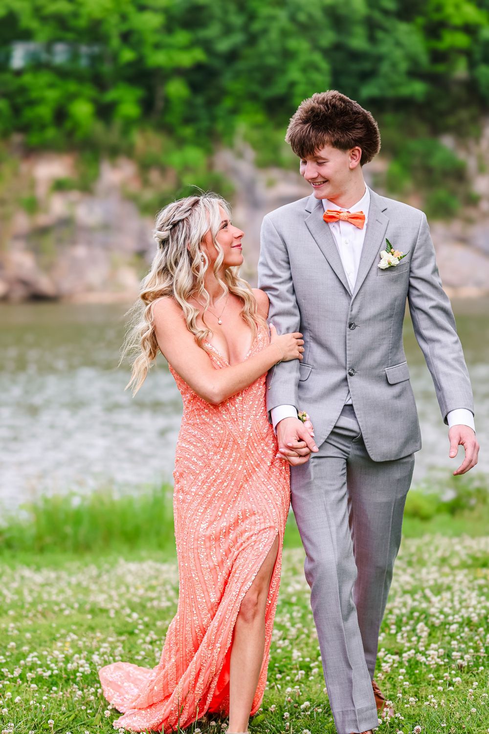 A candid image of a young prom couple walking and holding each others arms.