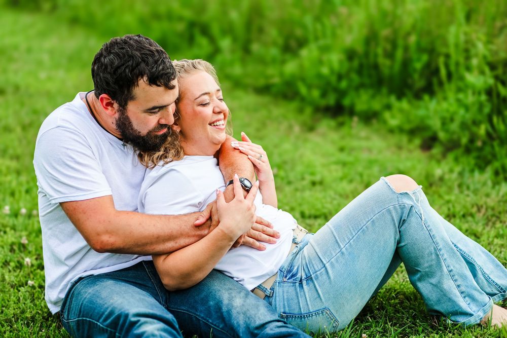 A candid image of a couple snuggling together in the grass.