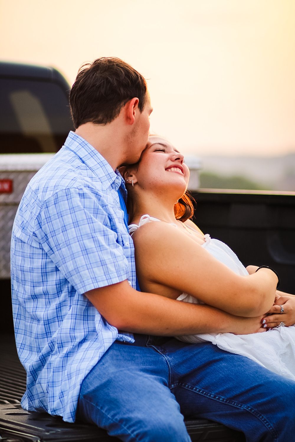 A candid lifestyle image of a couple sitting on the back of a truck together at Sunset / Golden hour.