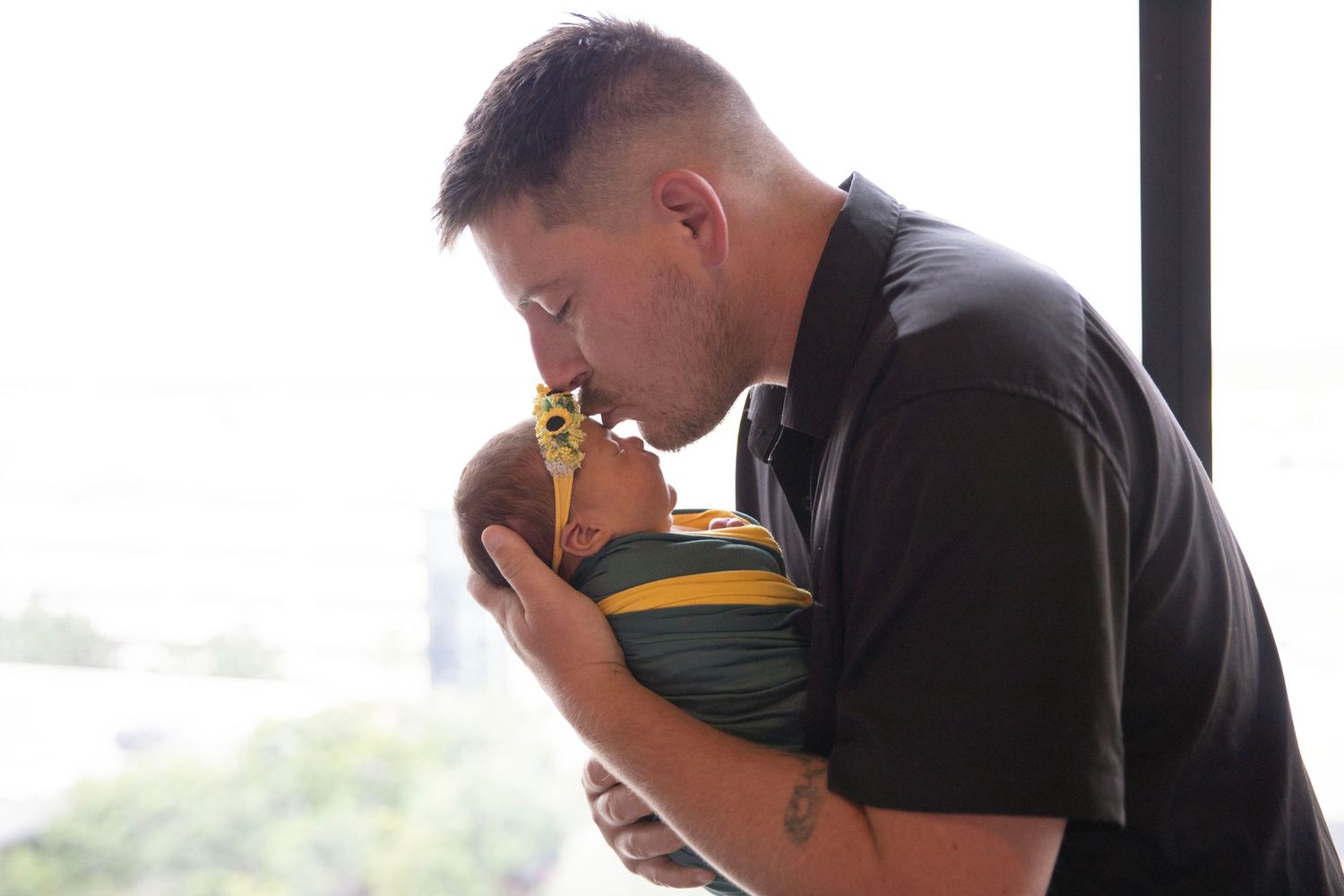 Father tenderly kissing his newborn baby while cradling the infant in his arms.