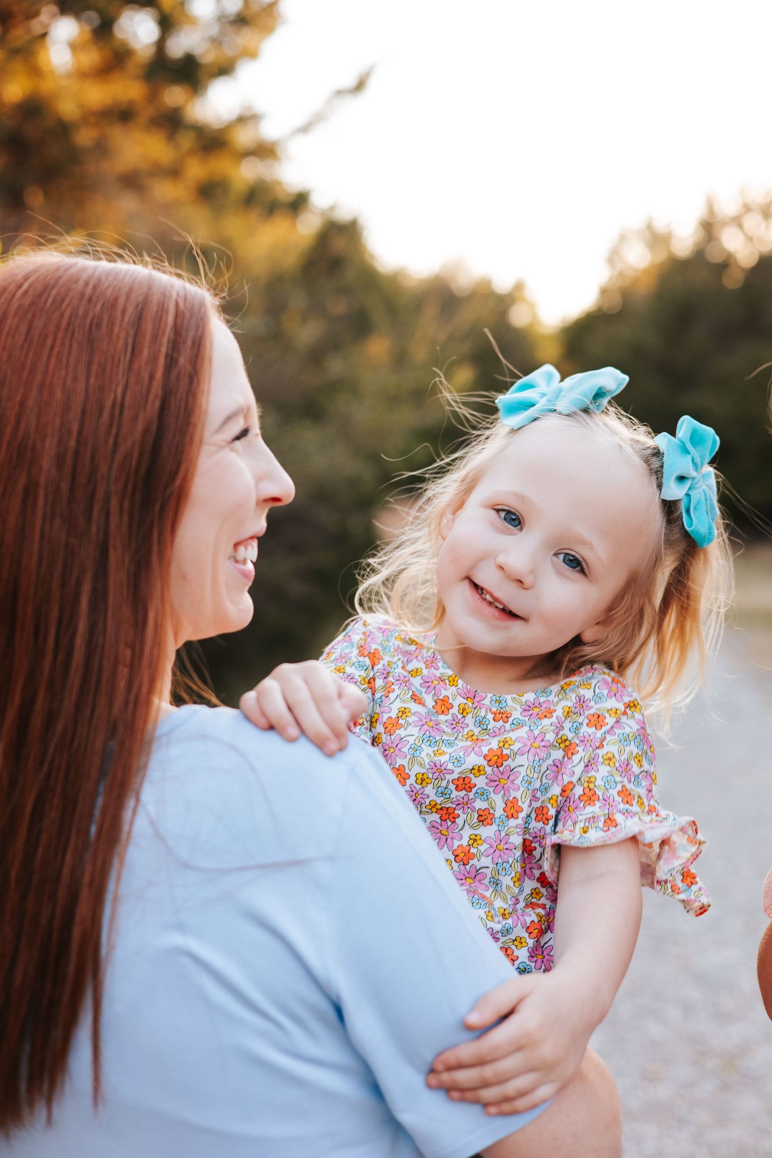 Mother and daughter share joyful moments during sunset photo session.