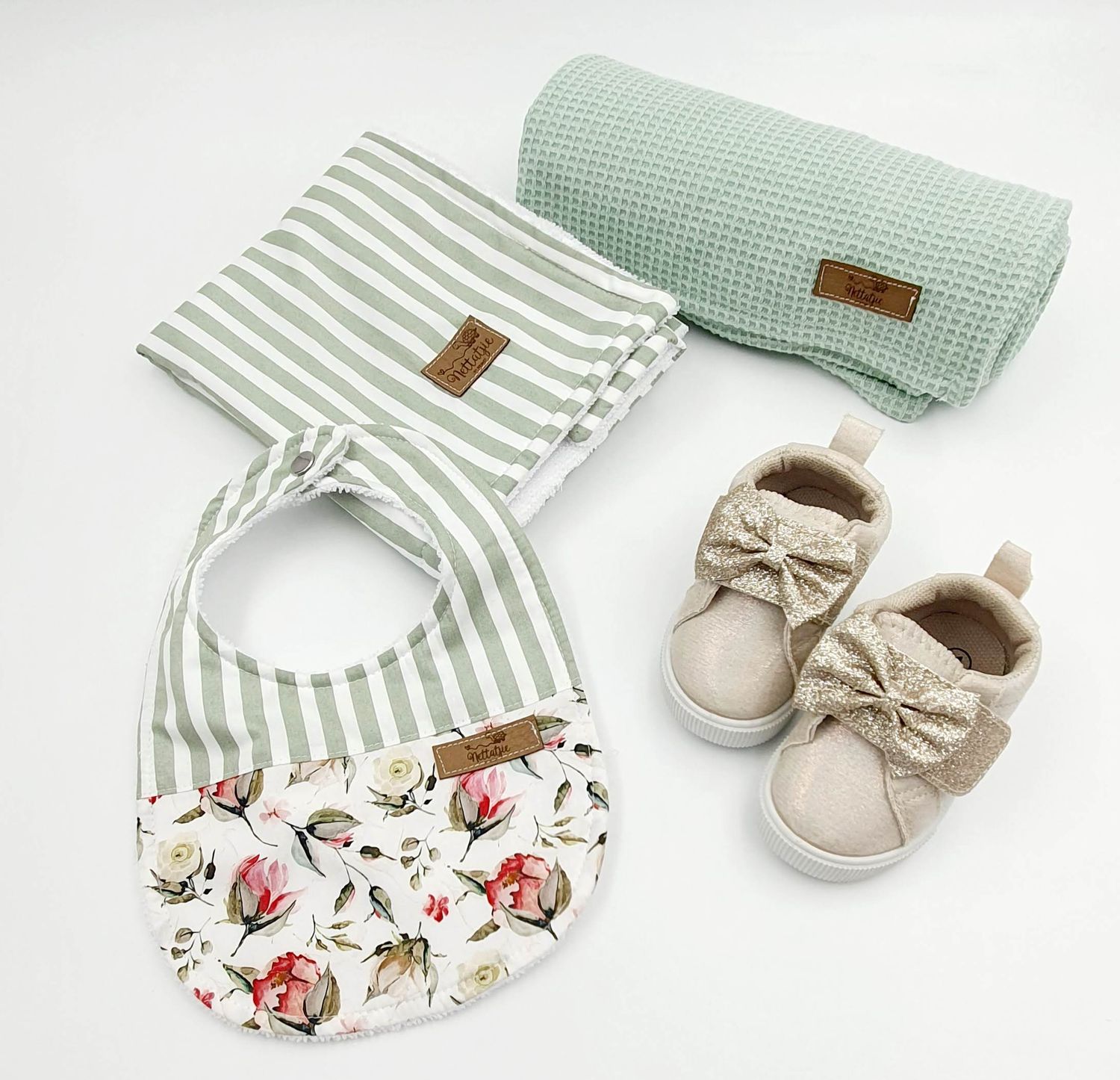 Mint green striped and floral print baby bibs with matching shoes arranged in sequence.