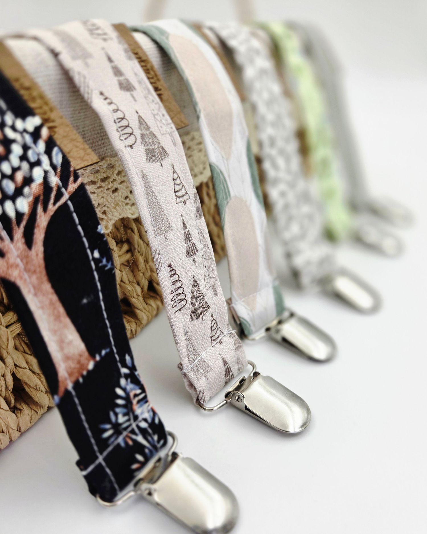 Close-up of metal pacifier clips with various fabric patterns attached.