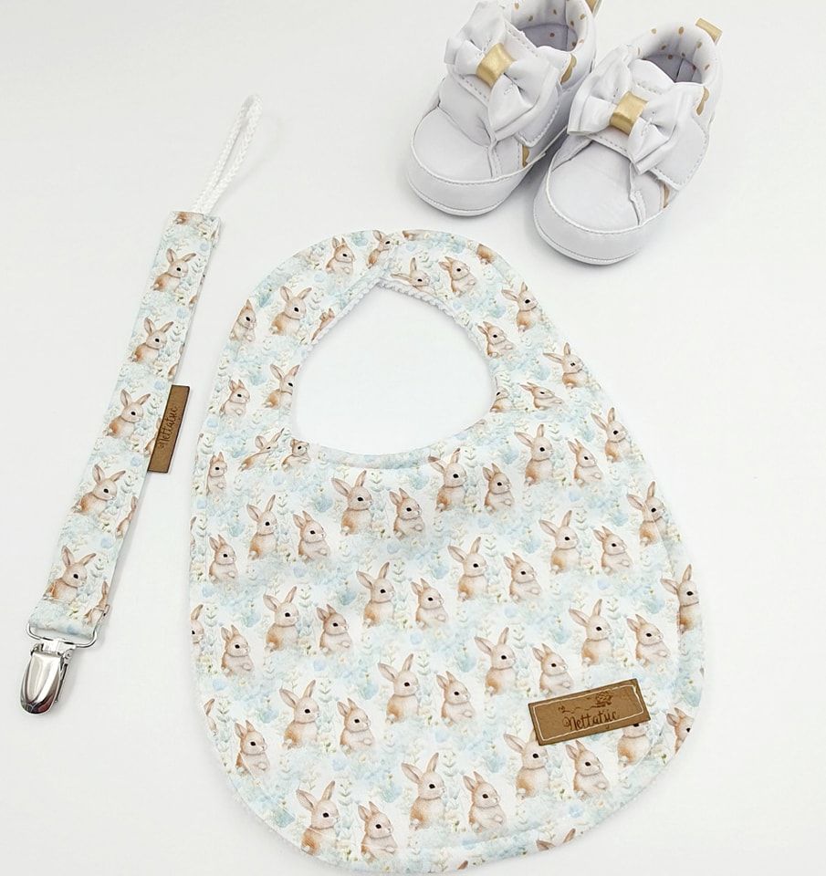 Baby bib and shoe set featuring bunny print pattern in soft pastel colors.