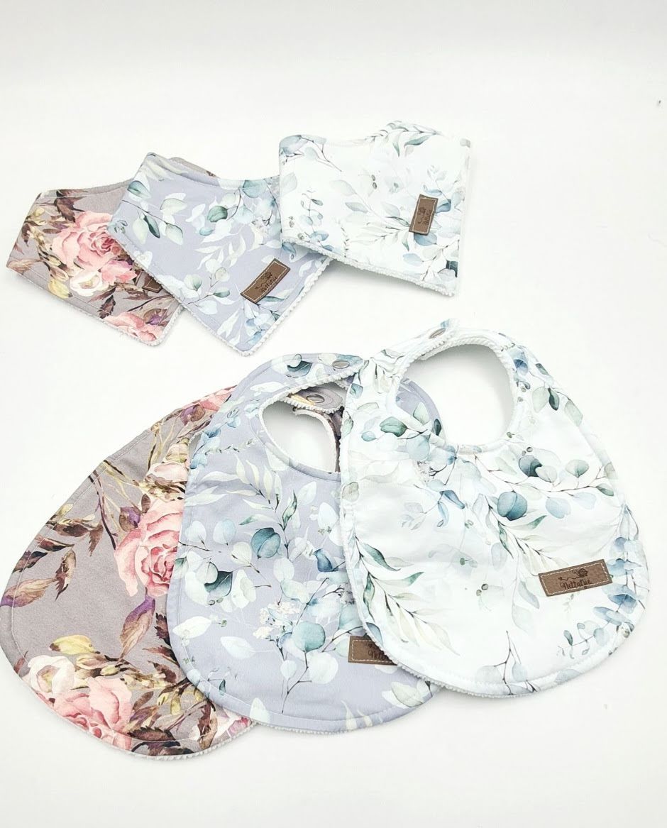 Collection of delicate floral print baby bibs with leather tags in soft pastel colors.
