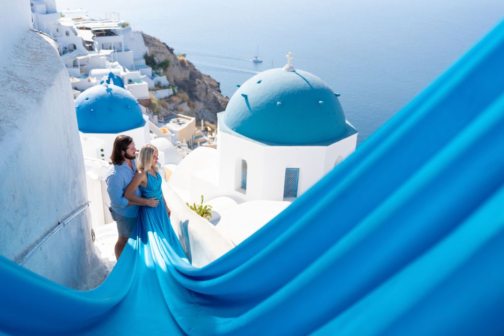 Flowing turquoise dress frames iconic blue domes and white buildings of Santorini.