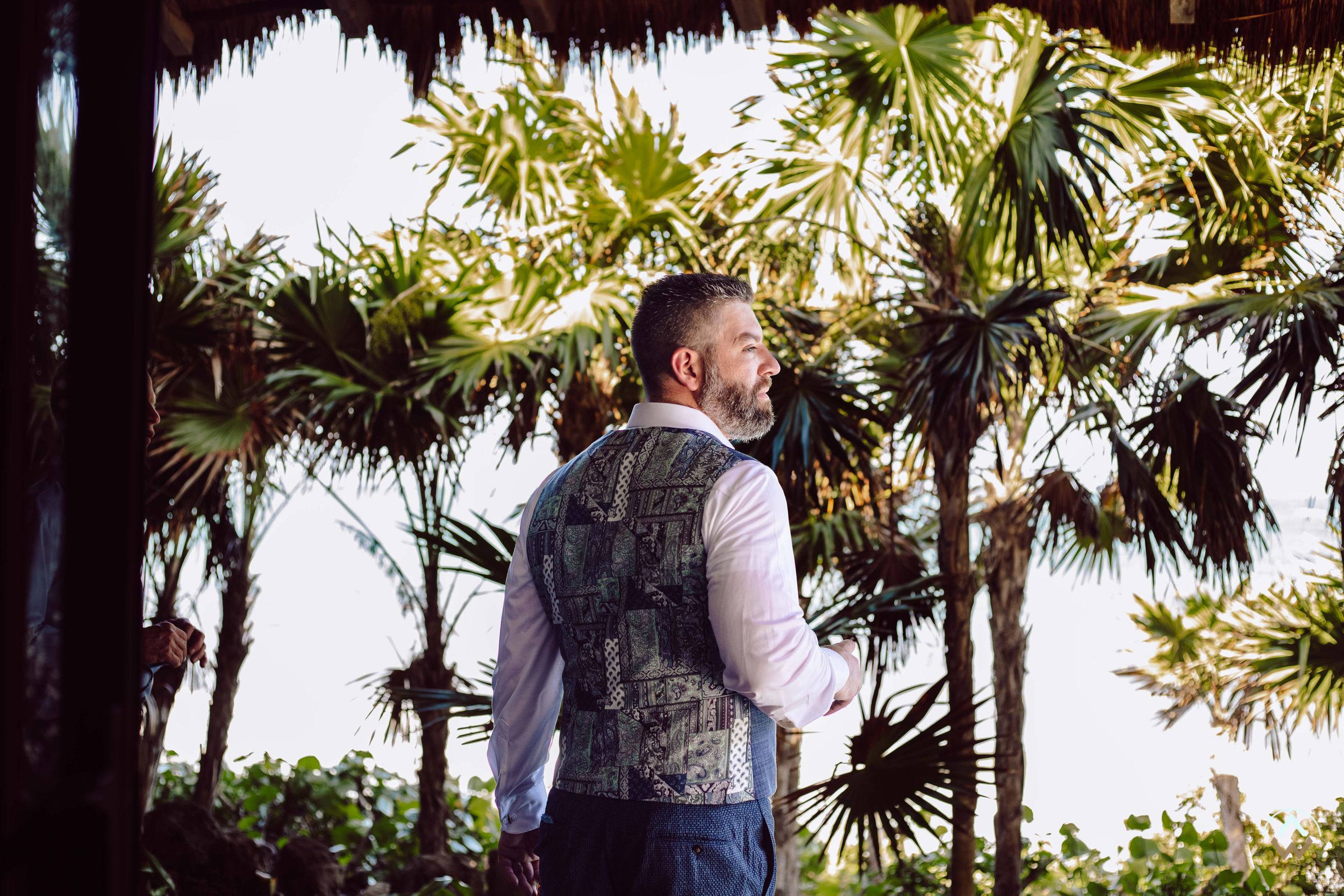 Palm trees line a beachside wedding venue with a thatched roof structure at sunset, Papaya Playa Tulum Wedding.