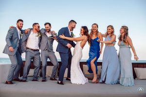 Wedding party poses playfully on white terrace overlooking ocean in coordinated blue attire, Papaya Playa Tulum Wedding.