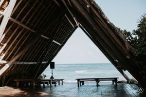 Angled view of a wooden thatched roof structure overlooking the ocean, Papaya Playa Tulum Wedding.