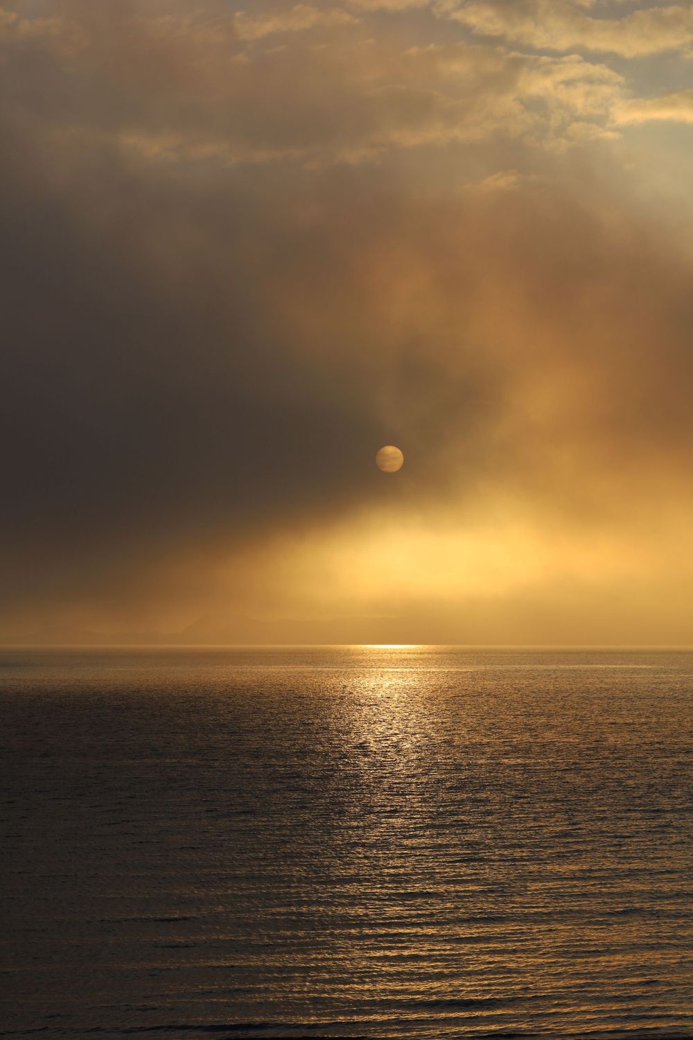 Golden sunset over calm ocean waters creates dramatic sky with glowing clouds.