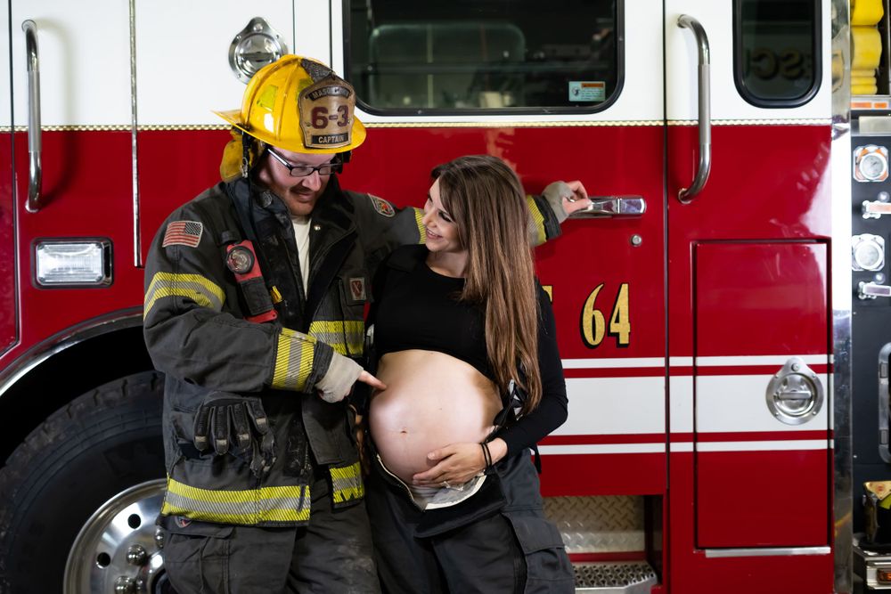 Firefighter poses in uniform beside red fire truck for professional photo.