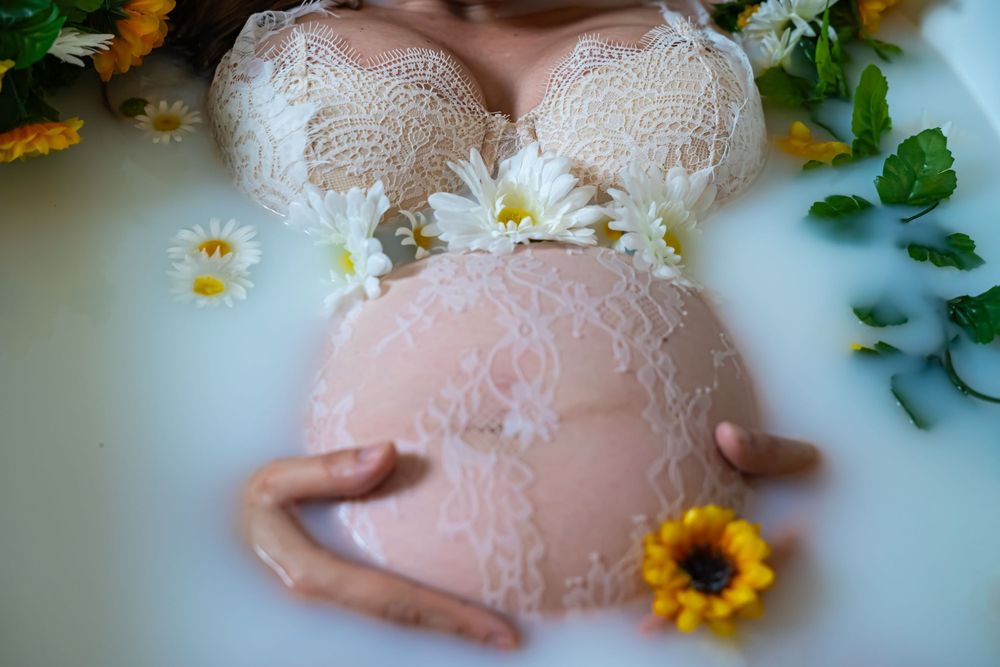 White lace maternity gown in a bathtub surrounded by sunflowers and daisies.