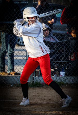 Baseball player in red and white uniform swinging bat during game.