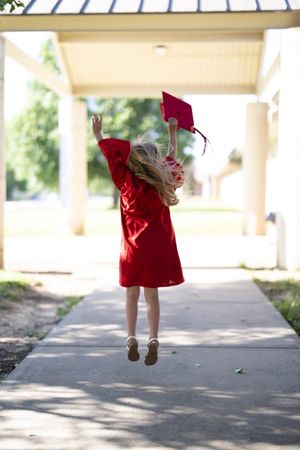 Sequence of child in red dress jumping and playing in covered walkway.