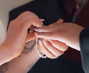 Close-up of hands exchanging rings during a wedding ceremony.