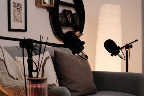 Podcast recording setup with microphones and lamp in a cozy corner.