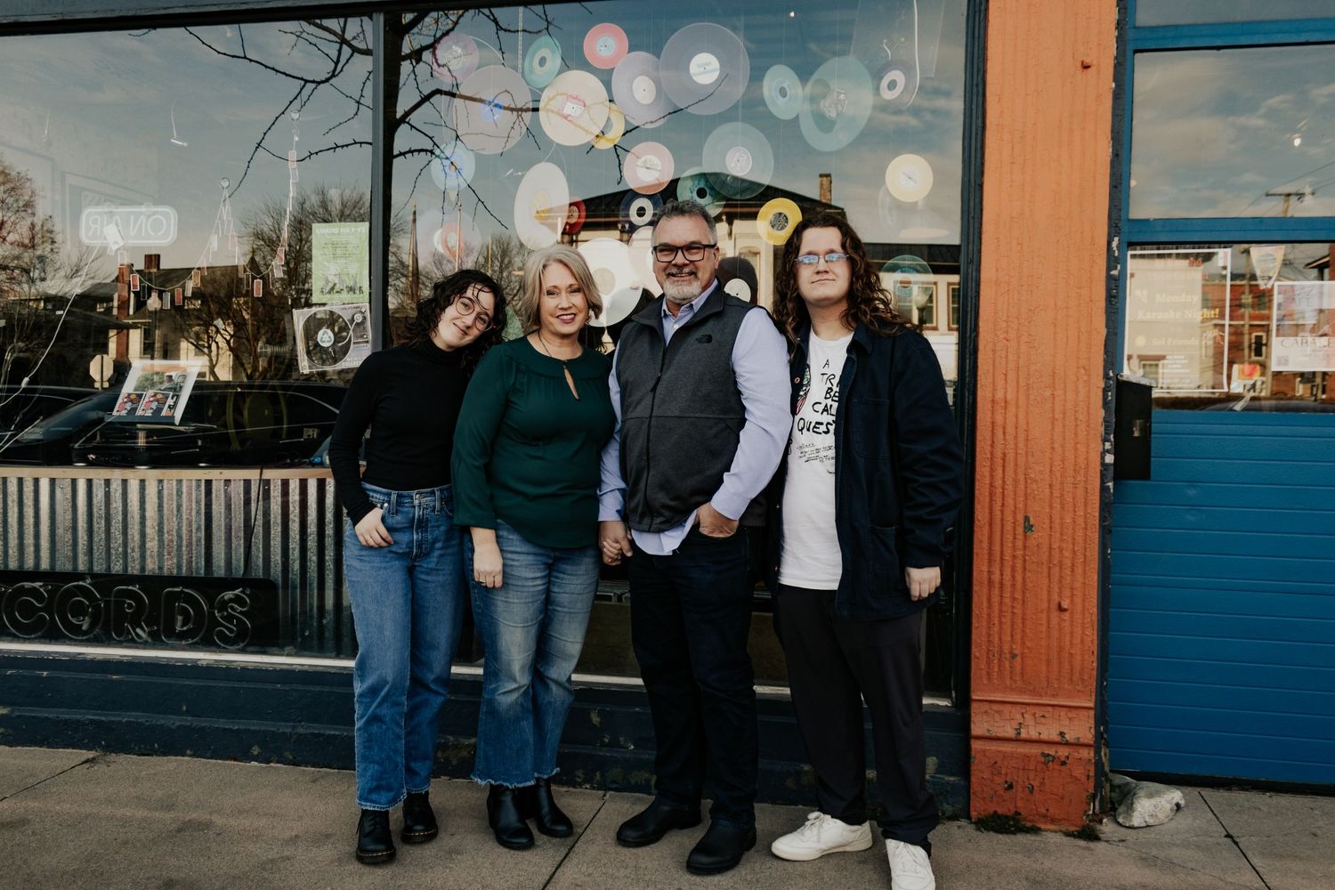 Family and friends gathered outside a blue building for casual group photos.