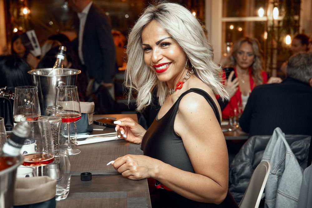 Person in black dress enjoying drinks at elegant restaurant bar.