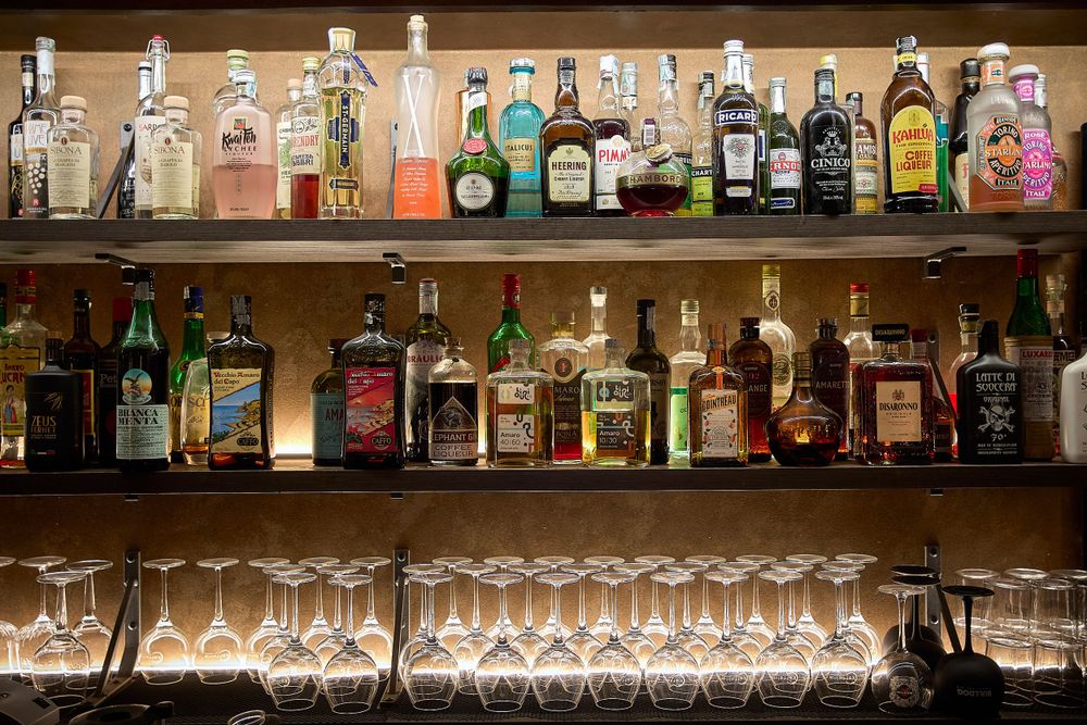 Well-stocked bar shelves display various liquor bottles with cocktail glasses arranged below.
