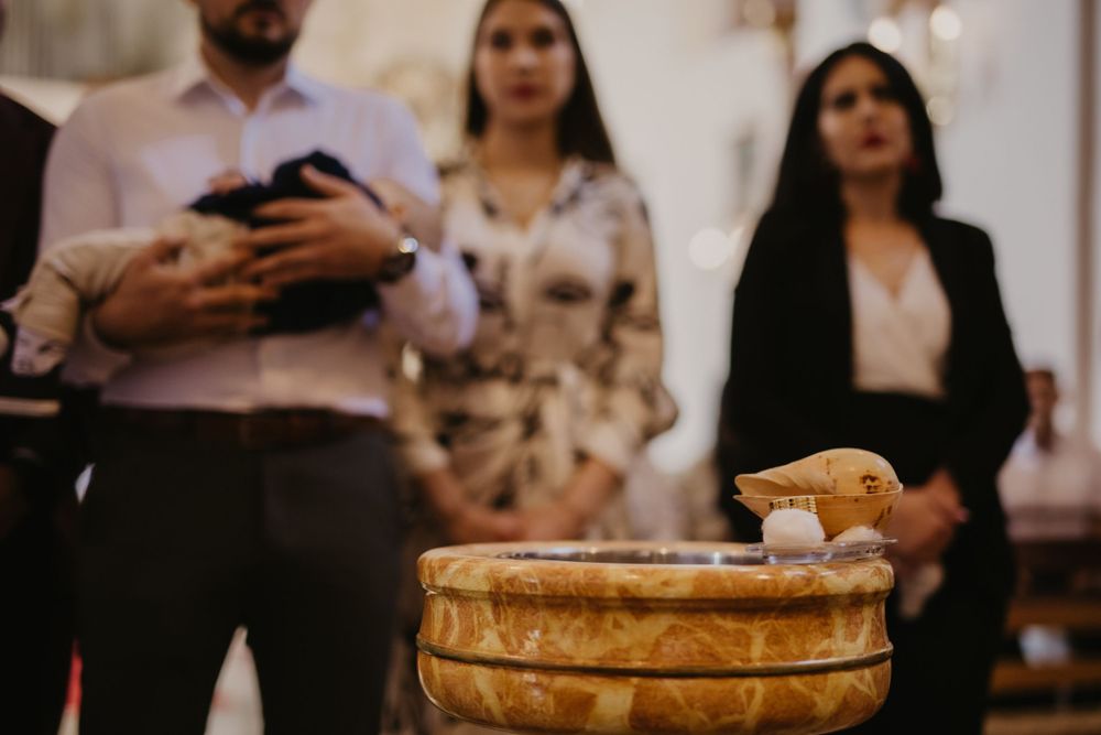 Baptismal font with holy water during religious ceremony.