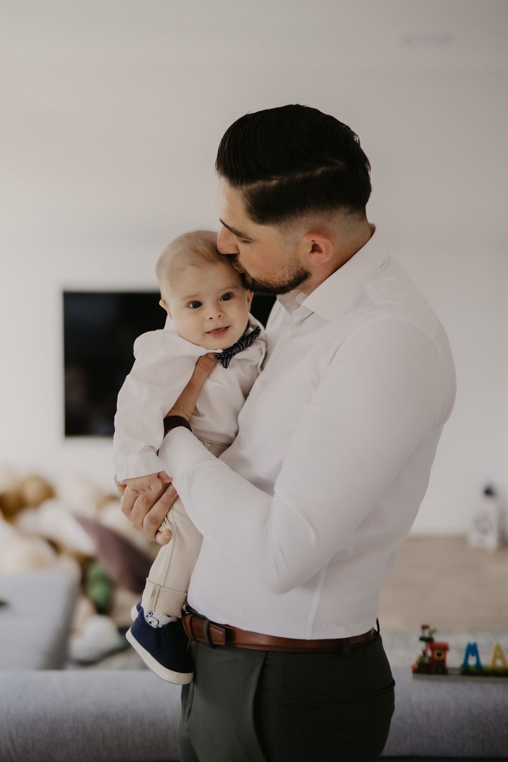 Tender moment between parent and baby both dressed in white.