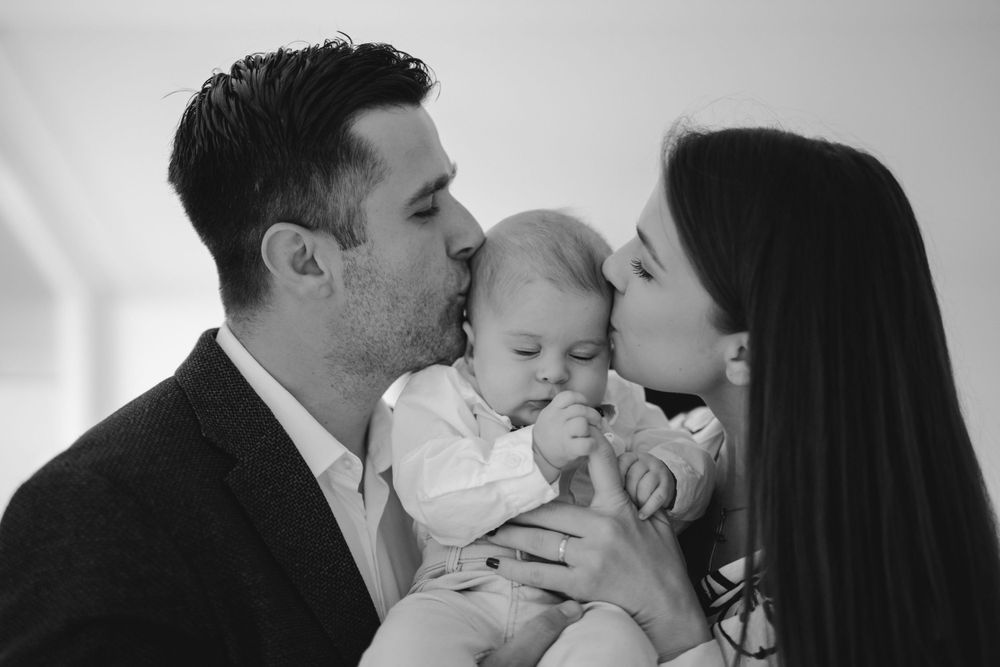 Intimate family portrait in black and white showing parents with baby.