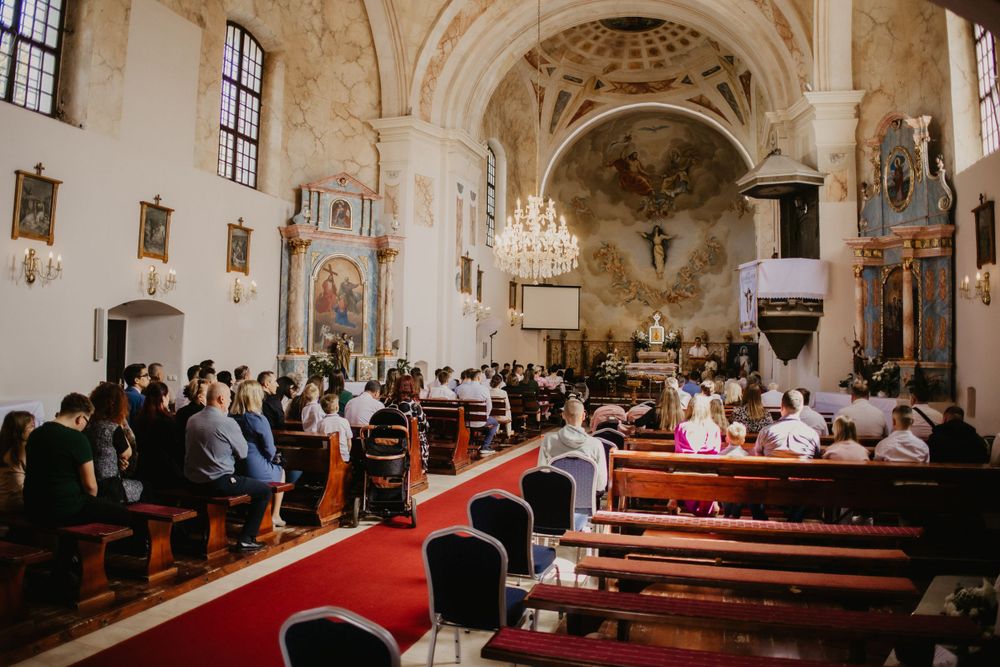 Interior of a historic church with vaulted ceilings and red carpet during a religious ceremony.