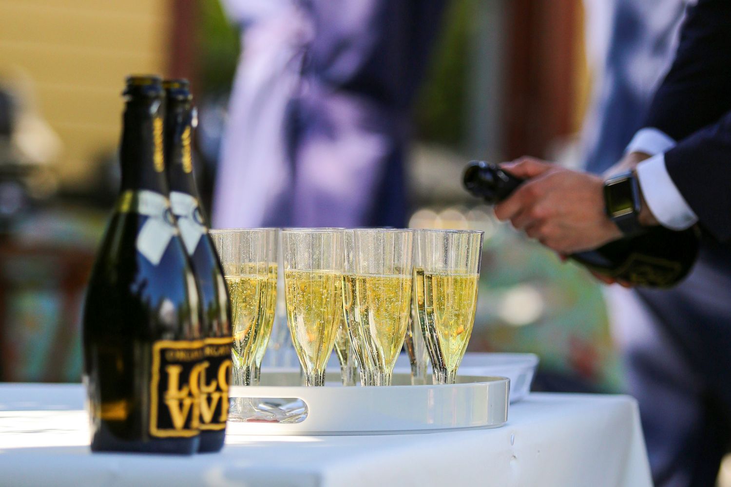 Row of champagne glasses lined up on white tablecloth at elegant event.
