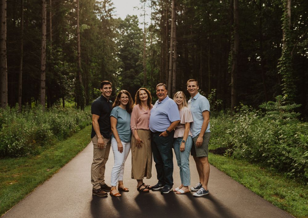 A multi-generational family group poses together on a forest path.