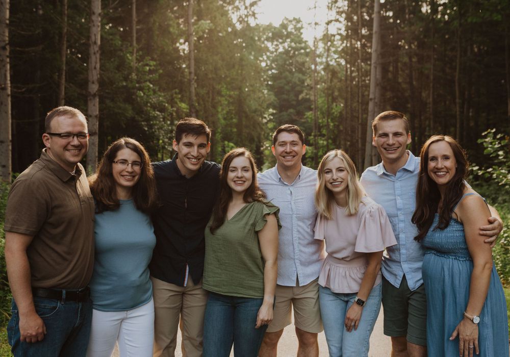 Large family group poses together on a wooded path during golden hour.